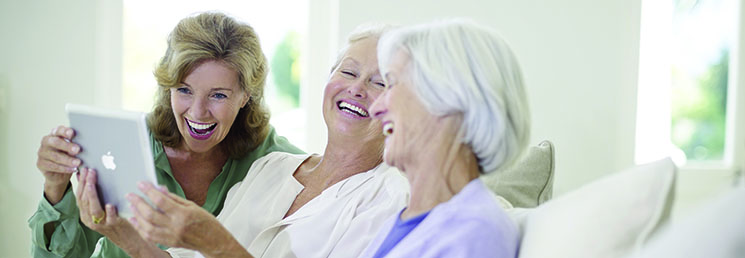 three women looking at a iPad and smiling